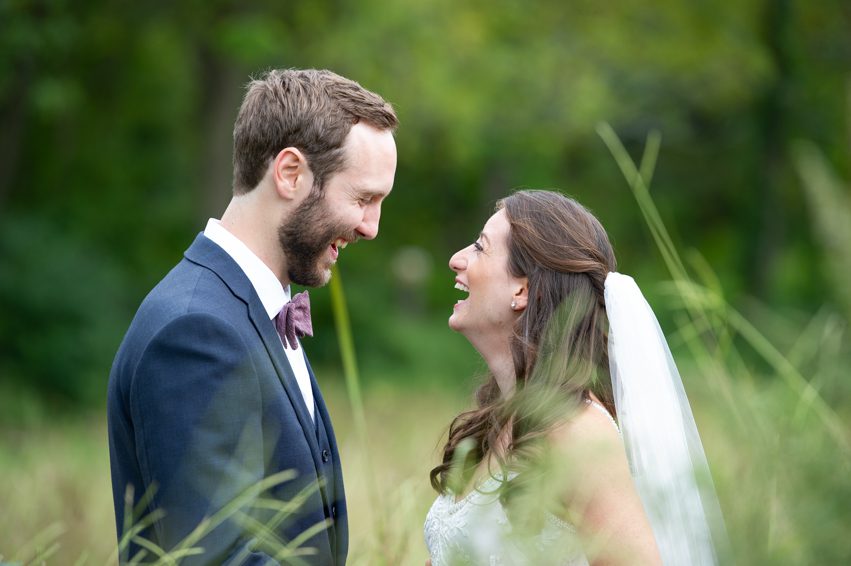couple in the fields facing each other laughing